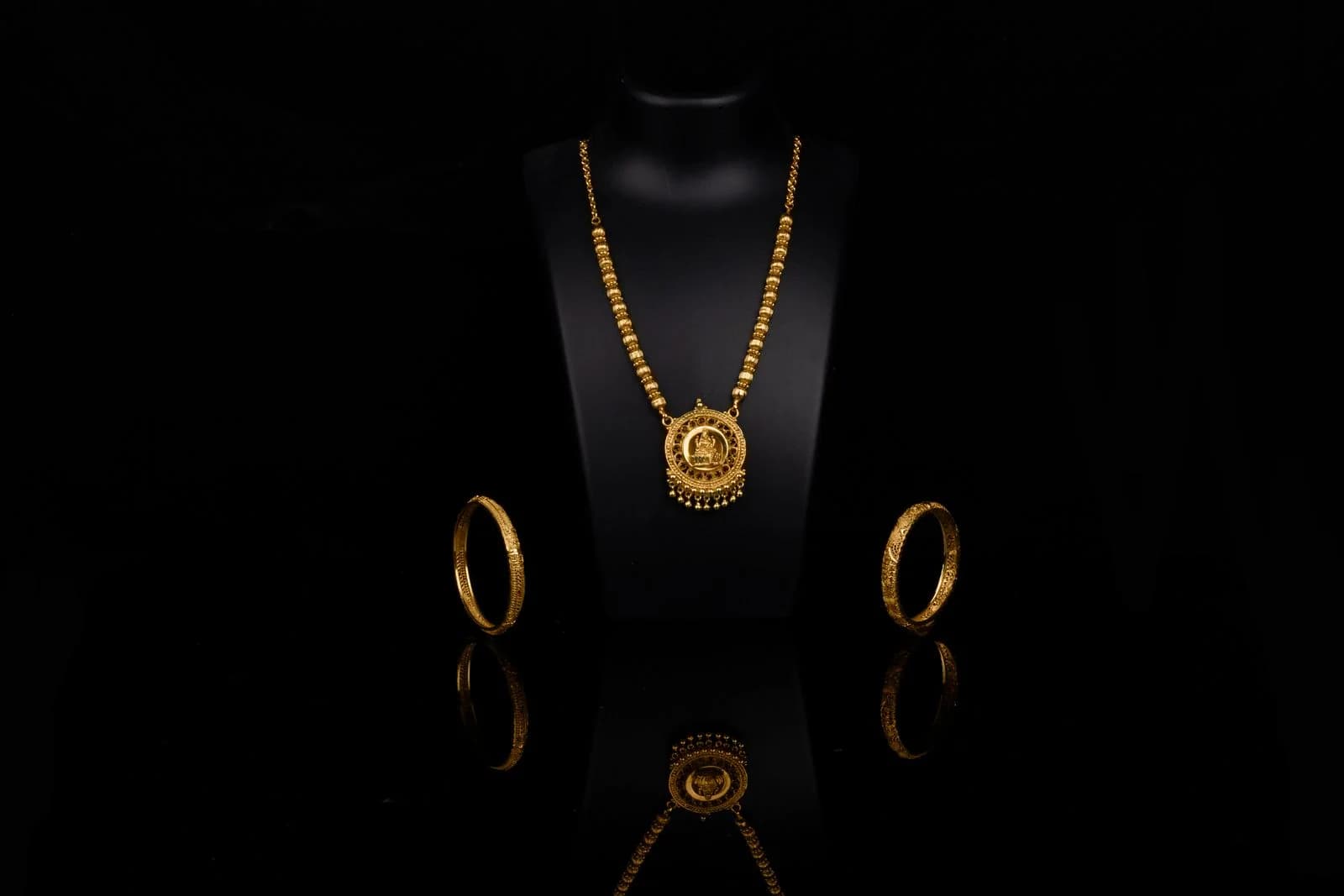 Gold jewellery arranged on a dark display